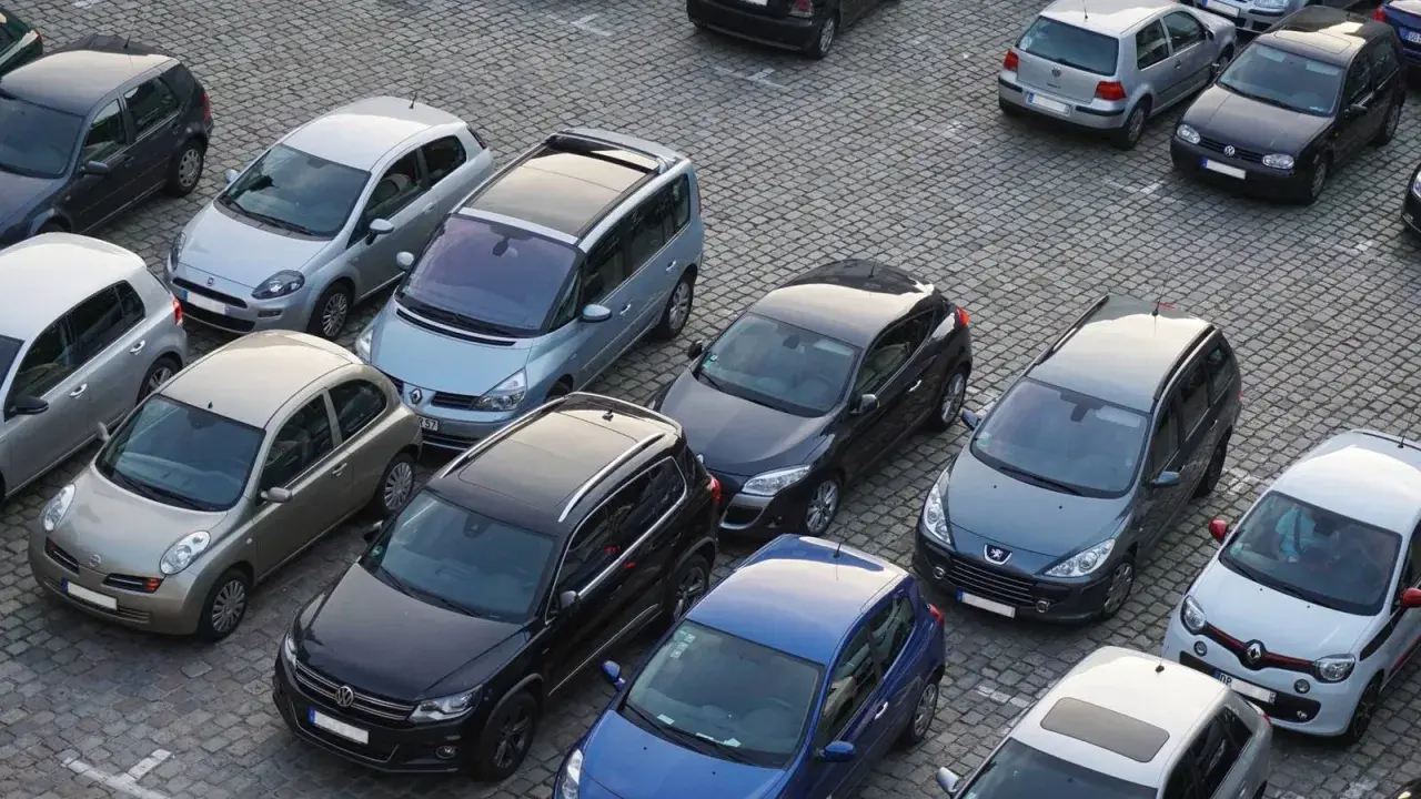 Na parkingu stoi wiele samochodów. Jeden z nich, srebrny Nissan, wygląda na uszkodzony. Czy to szkoda parkingowa? Policja już tu jest.