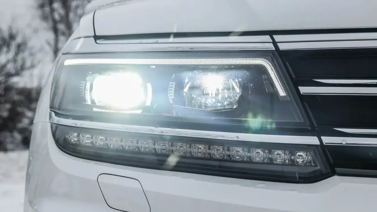 Reflektor samochodu z nowoczesnym oświetleniem adaptacyjnym, świecącym jasno w zimowy dzień.