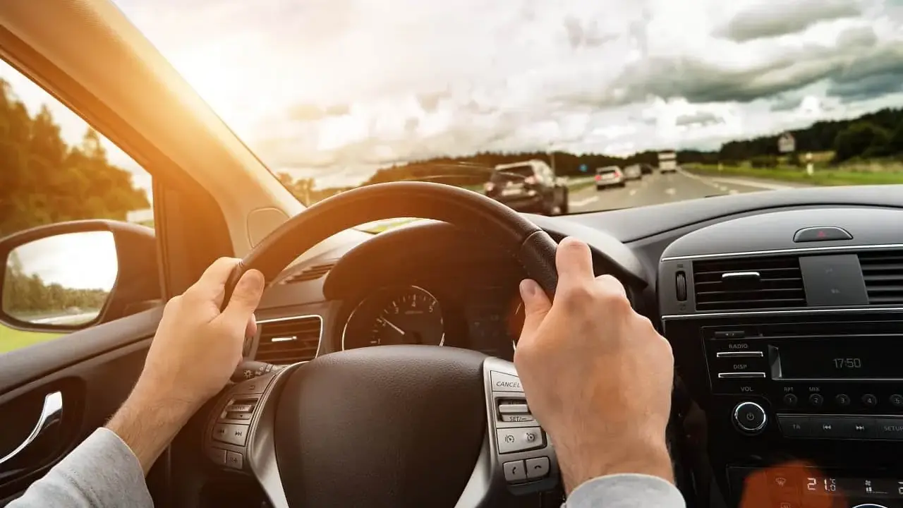 Kierowca trzyma kierownicę, jadąc autostradą. Wibracje kierownicy mogą sygnalizować objawy krzywej tarczy hamulcowej.