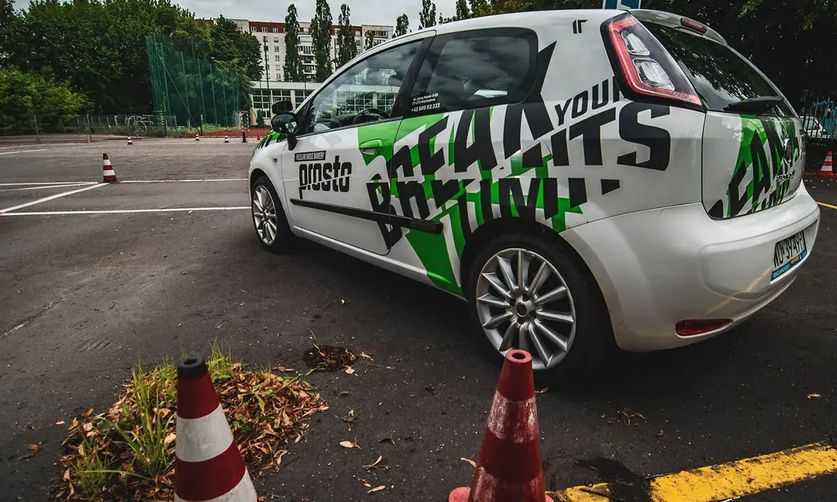 Samochód szkoleniowy z napisem "Prosto" i grafiką "Learn to Drive" na placu manewrowym. Idealne miejsce na jazdy doszkalające odlewnicza.
