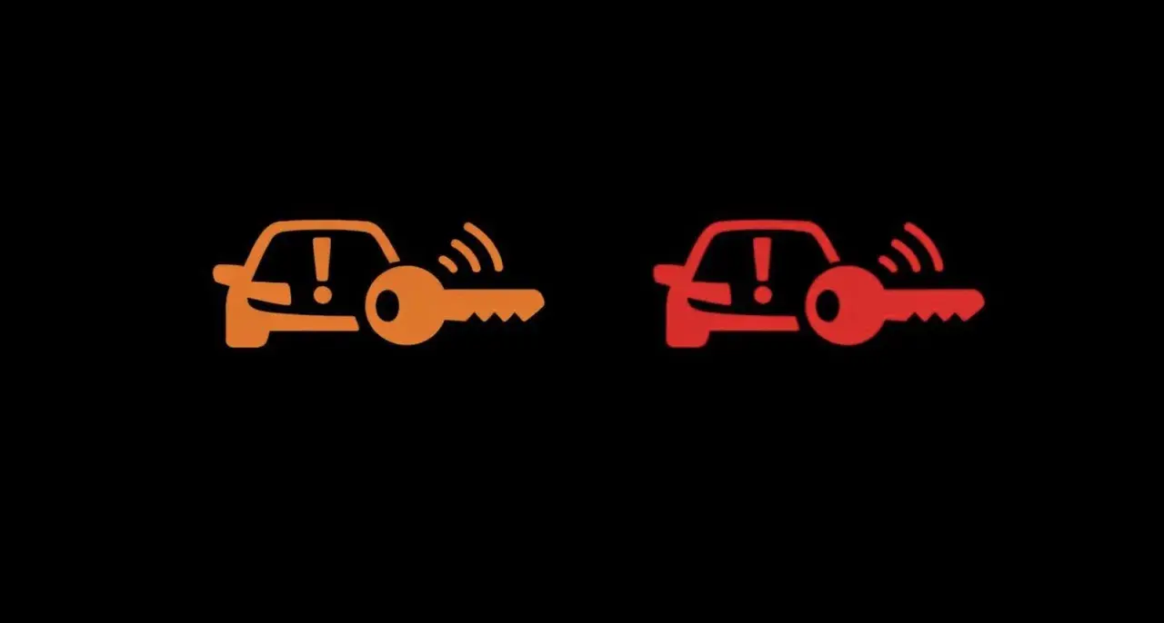 Pomarańczowa i czerwona kontrolka auto z kluczem, sygnalizujące problem z immobilizerem lub kluczykiem.