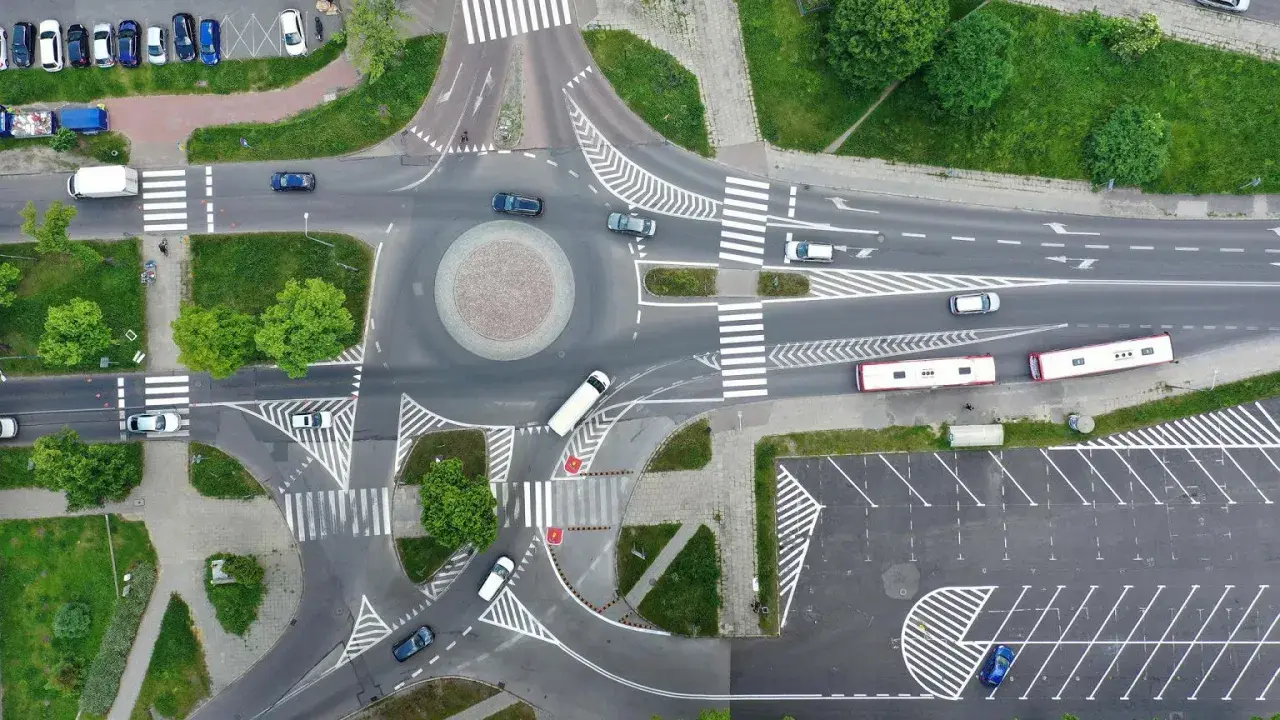 Widok z lotu ptaka na rondo i skrzyżowanie. Samochody i autobusy poruszają się po drogach. Zjazd z ronda na który pas?
