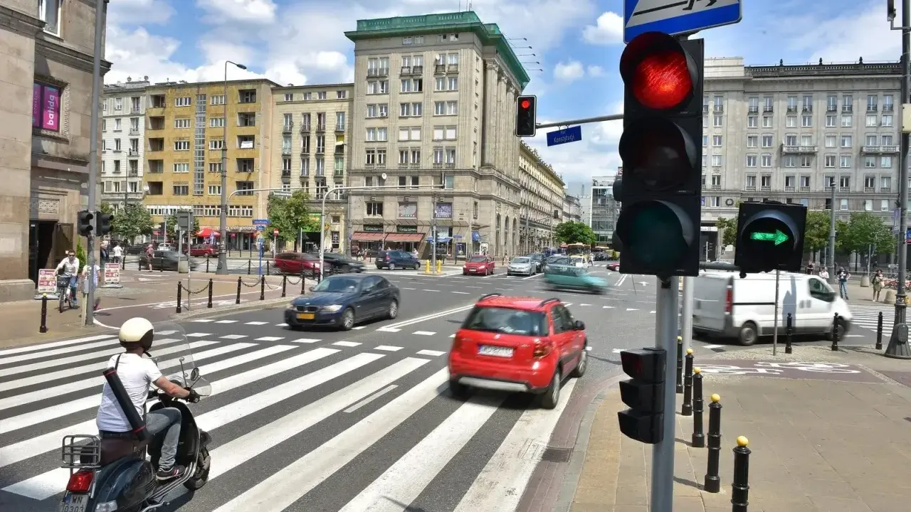 Zielona strzałka w prawo na sygnalizatorze świetlnym wskazuje kierunek jazdy. Ruch uliczny na skrzyżowaniu w słoneczny dzień.