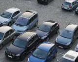 Na parkingu stoi wiele samochodów. Jeden z nich, srebrny Nissan, wygląda na uszkodzony. Czy to szkoda parkingowa? Policja już tu jest.