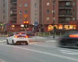 Biały samochód czeka na zielone światło. Czerwone światło oznacza punkty karne.