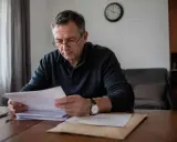 Mężczyzna w okularach analizuje dokumenty, martwiąc się o przedawnienie wykroczenia.