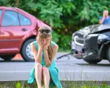 Kobieta w szoku po spowodowaniu wypadku z uszczerbkiem na zdrowiu powyżej 7 dni. Dwa uszkodzone samochody na drodze.
