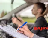 Paraliżujący stres przed egzaminem na prawo jazdy. Egzaminator notuje uwagi, młoda kobieta za kierownicą.