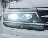 Reflektor samochodu z nowoczesnym oświetleniem adaptacyjnym, świecącym jasno w zimowy dzień.