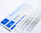 Dwa brytyjskie prawa jazdy i wydruk z danymi.