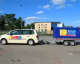 Jasny samochód z przyczepą szkoleniową, na której widnieje napis "KATEGORIE" i logo szkoły jazdy "Expert".