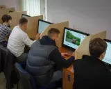 Ludzie siedzą przy komputerach, rozwiązując testy. To miejsce, gdzie można sprawdzić, kiedy można zdawać egzamin teoretyczny na prawo jazdy.