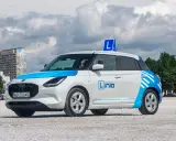 Biały samochód nauki jazdy z niebieskimi elementami i literą "L" na dachu. Dowiedz się, ile kosztują jazdy doszkalające w szkole Linia.