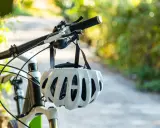 Biały kask rowerowy wisi na kierownicy roweru. Pamiętaj o kasku, by uniknąć mandatu za brak kasku na rowerze.