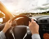 Kierowca trzyma kierownicę, jadąc autostradą. Wibracje kierownicy mogą sygnalizować objawy krzywej tarczy hamulcowej.