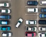 Widok z góry na parking. Po prawej stronie zaparkowane są samochody w rzędzie, jeden za drugim.