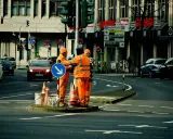 Pracownicy drogowi kierują ruchem, sugerując potencjalne odszkodowanie za brak dojazdu do posesji z powodu robót.