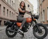Kobieta na stylowym motocyklu 125cc. Czy na motor 125 trzeba mieć prawo jazdy? To pytanie zadaje sobie wiele osób, które marzą o takiej maszynie.