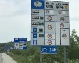 Znaki drogowe informujące o opłatach i limitach prędkości na drodze jednojezdniowej dwukierunkowej.
