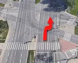 Czerwona strzałka pokazuje manewr zmiany pasa ruchu na skrzyżowaniu z przejściami dla pieszych.