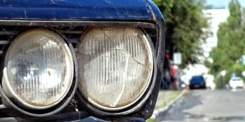 Stary, zaniedbany samochód z pajęczyną na reflektorach. Czy czasowe wyrejestrowanie pojazdu a OC to rozwiązanie dla takich aut?
