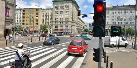 Zielona strzałka w prawo na sygnalizatorze świetlnym wskazuje kierunek jazdy. Ruch uliczny na skrzyżowaniu w słoneczny dzień.