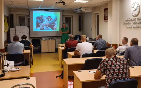 Szkolenie z zbijania punktów karnych. Wykładowczyni omawia rozwój choroby alkoholowej, a uczestnicy słuchają.