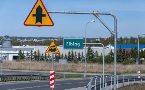 Uwaga na skrzyżowanie z drogą podporządkowaną i przejazd kolejowy. Znak "Elbląg" zaprasza do miasta.