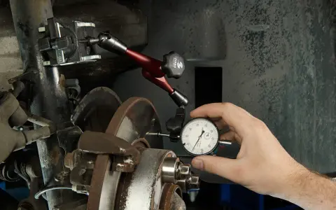 Mechanik sprawdza bicie przy hamowaniu, czy tarcze są proste. Wskaźnik zegarowy mierzy odchylenia.