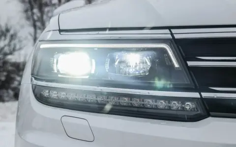 Reflektor samochodu z nowoczesnym oświetleniem adaptacyjnym, świecącym jasno w zimowy dzień.