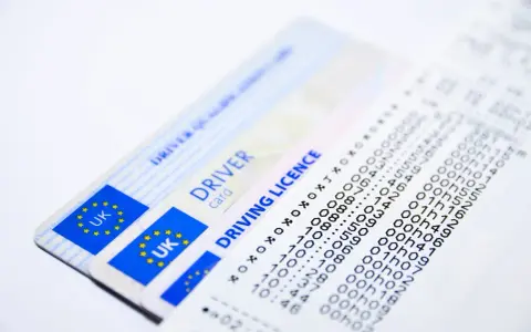 Dwa brytyjskie prawa jazdy i wydruk z danymi.
