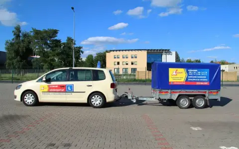 Jasny samochód z przyczepą szkoleniową, na której widnieje napis "KATEGORIE" i logo szkoły jazdy "Expert".