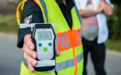 Policjant trzyma alkomat, który pokazuje wynik 0.93. To urządzenie pomaga sprawdzić, co neutralizuje alkohol w wydychanym powietrzu.