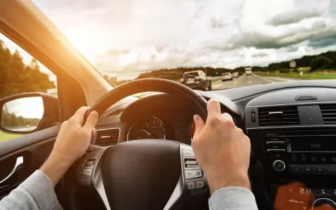 Kierowca trzyma kierownicę, jadąc autostradą. Wibracje kierownicy mogą sygnalizować objawy krzywej tarczy hamulcowej.