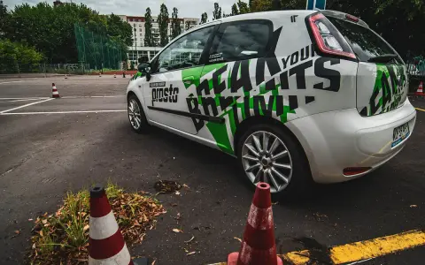 Samochód szkoleniowy z napisem "Prosto" i grafiką "Learn to Drive" na placu manewrowym. Idealne miejsce na jazdy doszkalające odlewnicza.