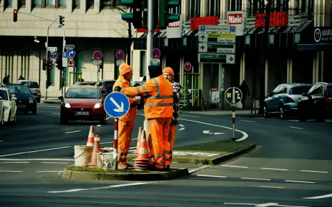 Pracownicy drogowi kierują ruchem, sugerując potencjalne odszkodowanie za brak dojazdu do posesji z powodu robót.