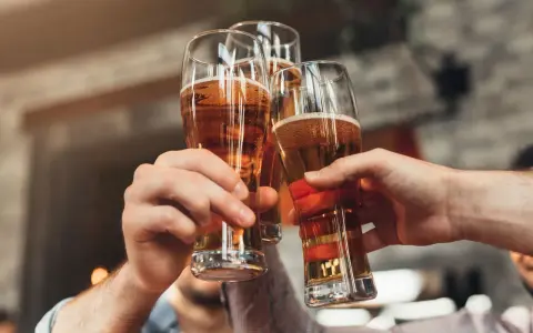 Trzy ręce wznoszą kufle z piwem do toastu. Zastanawiasz się, ile to piw, gdy masz 0,2 promila?