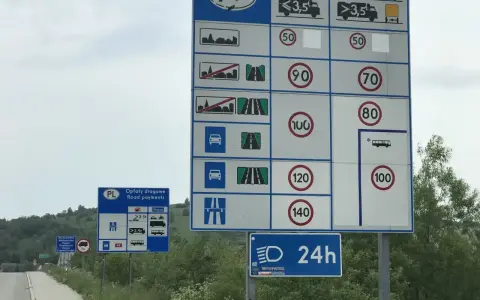 Znaki drogowe informujące o opłatach i limitach prędkości na drodze jednojezdniowej dwukierunkowej.