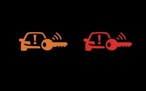 Pomarańczowa i czerwona kontrolka auto z kluczem, sygnalizujące problem z immobilizerem lub kluczykiem.