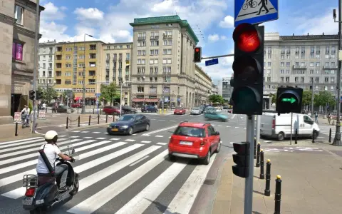 Zielona strzałka w prawo na sygnalizatorze świetlnym wskazuje kierunek jazdy. Ruch uliczny na skrzyżowaniu w słoneczny dzień.
