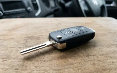 Kluczyk samochodowy z immobilizerem leży na drewnianym blacie. W tle widać wnętrze pojazdu.