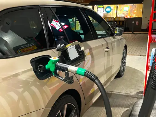 Tankowanie samochodu, zielony pistolet paliwa wlewa się do baku. Obawy o złej jakości paliwo diesel objawy mogą pojawić się po takiej wizycie na stacji.