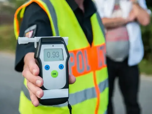 Policjant trzyma alkomat, który pokazuje wynik 0.93. To urządzenie pomaga sprawdzić, co neutralizuje alkohol w wydychanym powietrzu.
