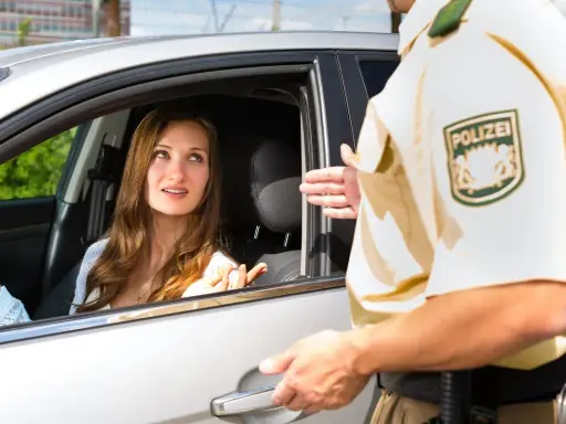 Kobieta w samochodzie rozmawia z policjantem, który prawdopodobnie wystawia mandaty w Niemczech.