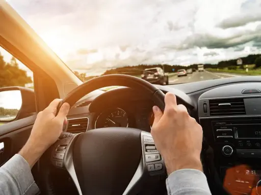 Kierowca trzyma kierownicę, jadąc autostradą. Wibracje kierownicy mogą sygnalizować objawy krzywej tarczy hamulcowej.