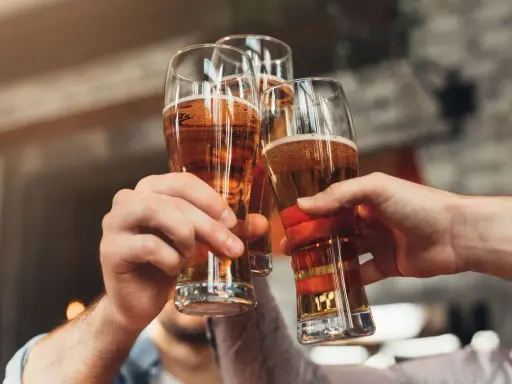 Trzy ręce wznoszą kufle z piwem do toastu. Zastanawiasz się, ile to piw, gdy masz 0,2 promila?
