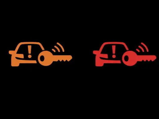 Pomarańczowa i czerwona kontrolka auto z kluczem, sygnalizujące problem z immobilizerem lub kluczykiem.