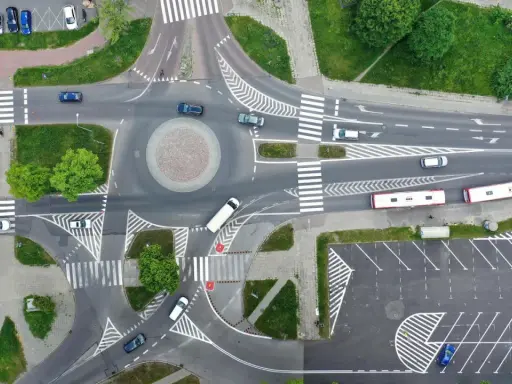 Widok z lotu ptaka na rondo i skrzyżowanie. Samochody i autobusy poruszają się po drogach. Zjazd z ronda na który pas?