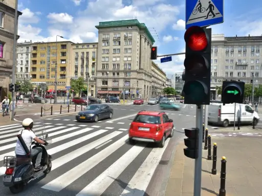 Zielona strzałka w prawo na sygnalizatorze świetlnym wskazuje kierunek jazdy. Ruch uliczny na skrzyżowaniu w słoneczny dzień.