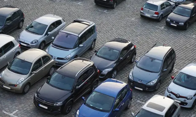 Na parkingu stoi wiele samochodów. Jeden z nich, srebrny Nissan, wygląda na uszkodzony. Czy to szkoda parkingowa? Policja już tu jest.